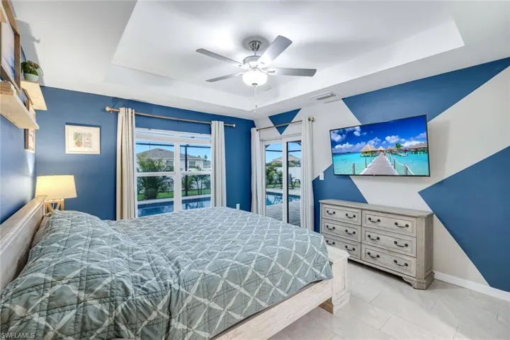 Bedroom with a tray ceiling, a ceiling fan, and access to exterior