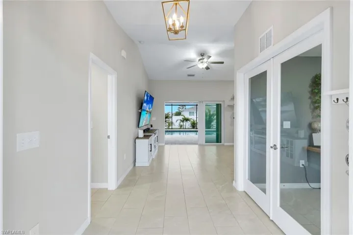 Corridor featuring a chandelier, light tile patterned flooring, and lofted ceiling