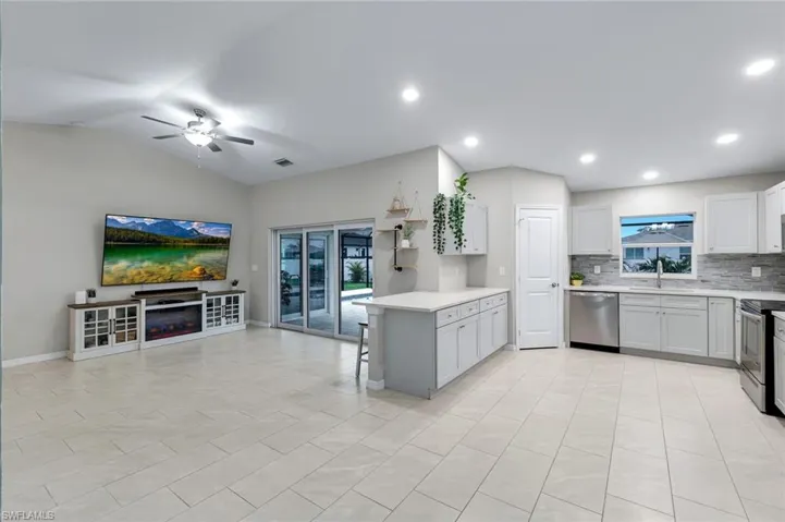 Kitchen featuring a kitchen bar, ceiling fan, a peninsula, stainless steel appliances, and open floor plan