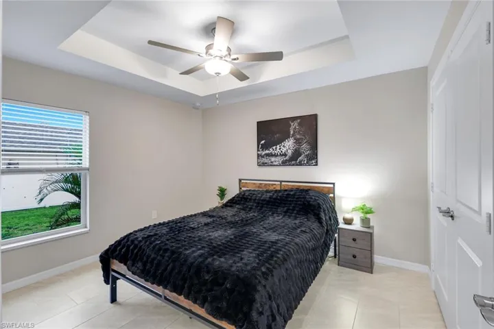 Bedroom featuring a tray ceiling, ceiling fan, and light tile patterned floors
