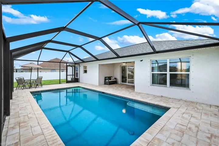 View of swimming pool with a sunroom, patio surround, a lanai, and outdoor dining space