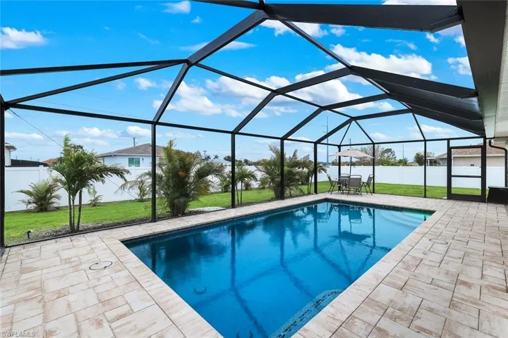 Swimming pool with a fenced backyard, a sunroom, glass enclosure, and a patio area