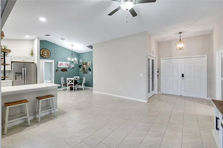 Kitchen featuring stainless steel fridge with ice dispenser, a chandelier, white cabinetry, lofted ceiling, and ceiling fan