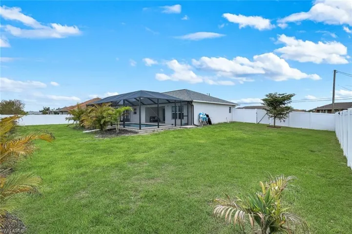 Rear view of house with a fenced backyard, glass enclosure, a swimming pool, stucco siding, and a sunroom