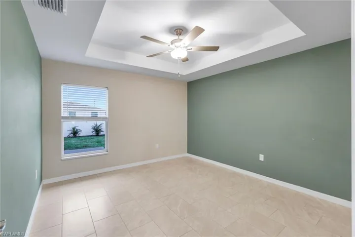 Empty room featuring ceiling fan and a tray ceiling