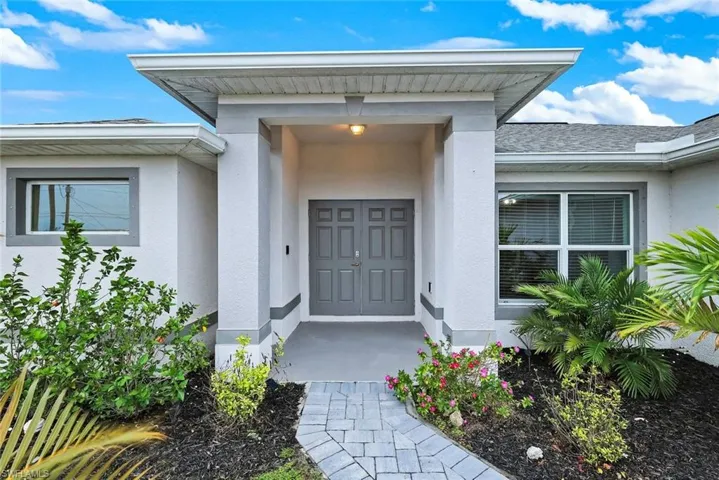 Entrance to property with stucco siding and a shingled roof