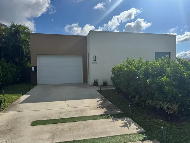 View of front of house with stucco siding, driveway, and a garage