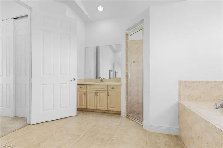 Bathroom featuring tile patterned flooring, a shower with door, and vanity