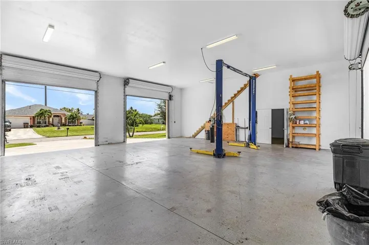 View of garage from the back right towards the front featuring the cart lift and 2 rolling doors in the front.