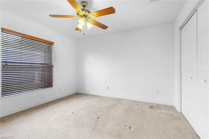 Unfurnished bedroom featuring ceiling fan, a closet, and light carpet.