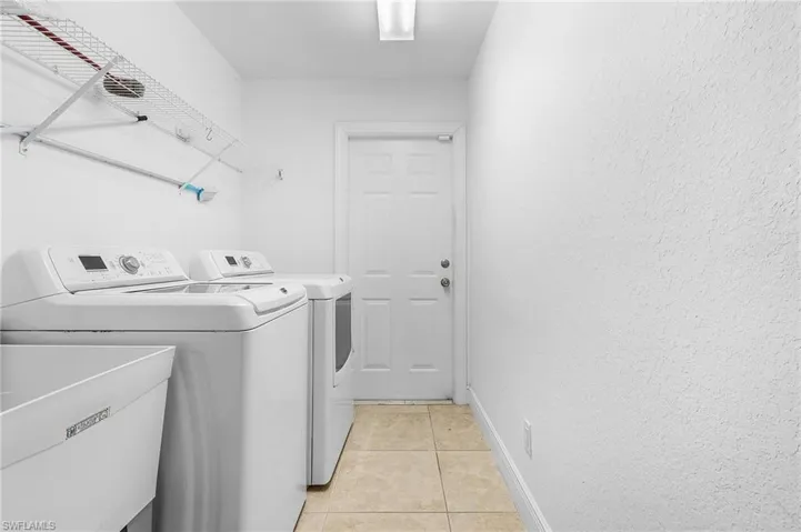 Laundry room with light tile patterned flooring, sink, and washing machine and dryer