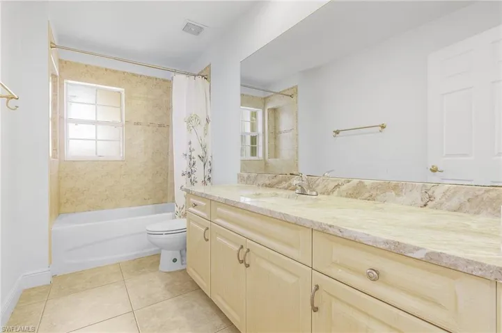 Full bathroom with vanity, tile patterned flooring, toilet, and shower / tub combo.