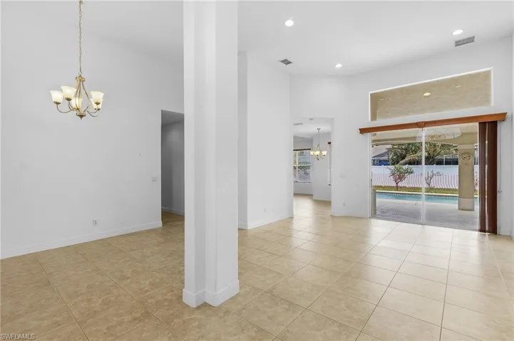 View of the dinning and living area towards pool, featuring a high ceiling and a chandelier.