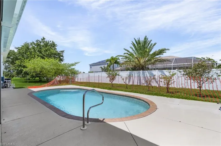 View of swimming pool with a lawn and a deck area.