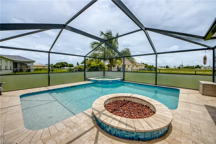 View of swimming pool featuring a patio area, a pool with connected hot tub, and glass enclosure