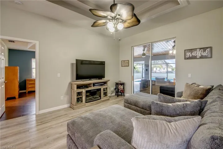 Living area with light wood-style floors, ceiling fan, and healthy amount of natural light