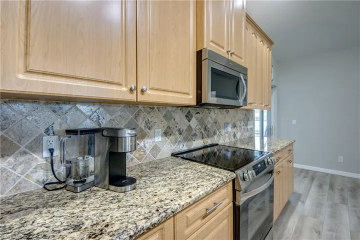 Kitchen featuring stainless steel appliances, light wood-style floors, light brown cabinets, and tasteful backsplash