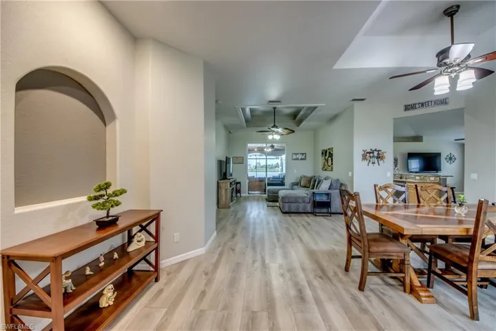 Dining room featuring ceiling fan, light wood-type flooring, and a raised ceiling