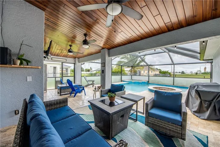 View of patio featuring ceiling fan, an outdoor living space, a pool with connected hot tub, glass enclosure, and a grill