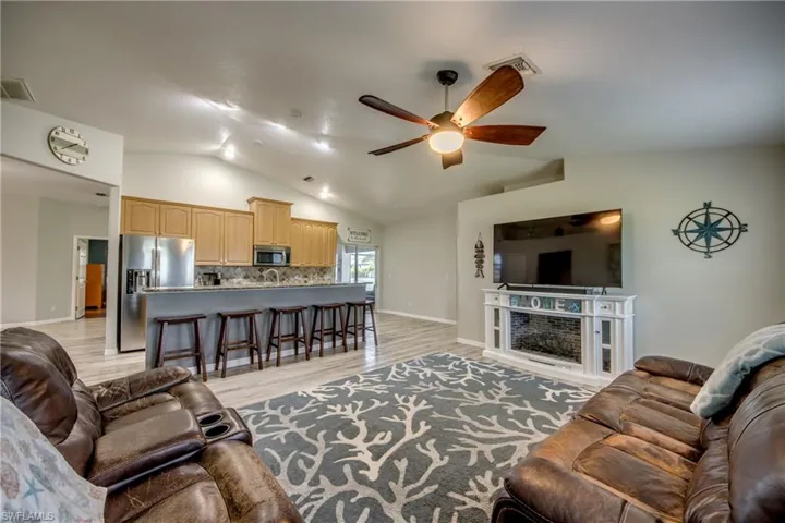 Living area with ceiling fan, lofted ceiling, and light wood-type flooring