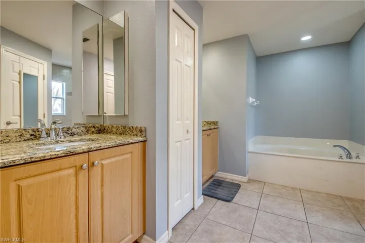 Full bath with vanity, a bath, tile patterned flooring, and a closet
