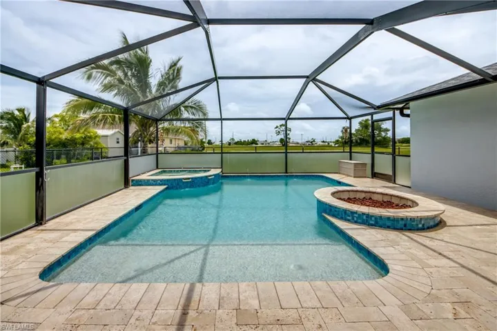 View of swimming pool featuring a pool with connected hot tub, glass enclosure, and a patio