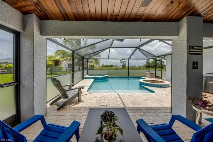View of pool with a pool with connected hot tub, a patio, and glass enclosure