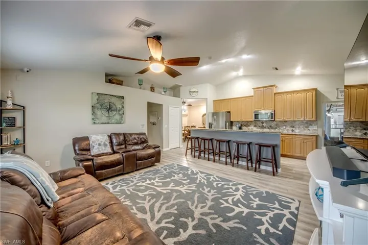 Living room featuring light wood-style floors, lofted ceiling, and ceiling fan