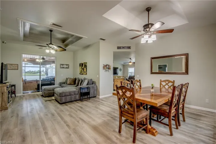Dining space featuring a raised ceiling, a ceiling fan, and light wood-type flooring