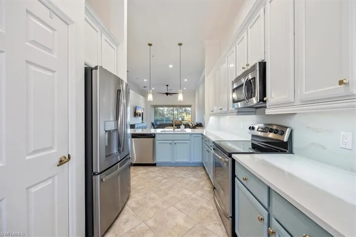 Kitchen featuring stainless steel appliances, hanging light fixtures, white cabinets, recessed lighting, and light tile patterned flooring