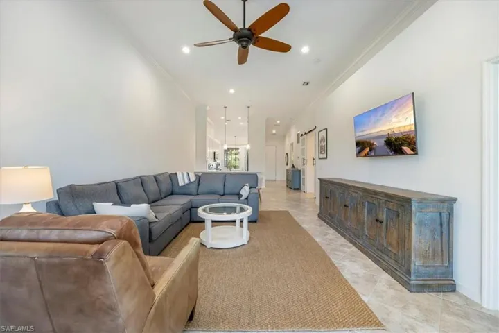 Living room with ornamental molding, recessed lighting, a ceiling fan, and light tile patterned floors