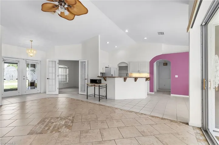 Kitchen featuring french doors, a breakfast bar area, light tile patterned floors, white cabinets, and a ceiling fan