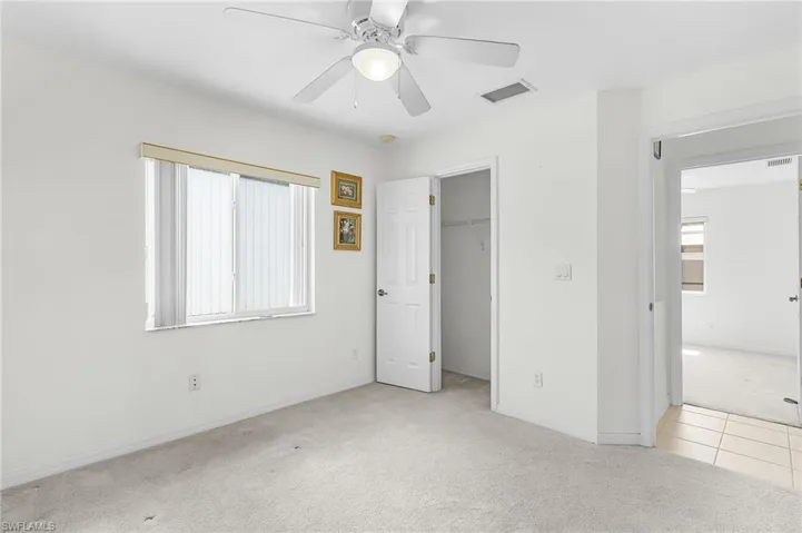 Unfurnished bedroom with light carpet, a spacious closet, and ceiling fan