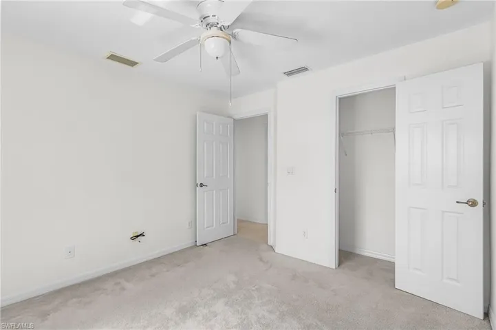 Unfurnished bedroom with light carpet, a ceiling fan, and a closet