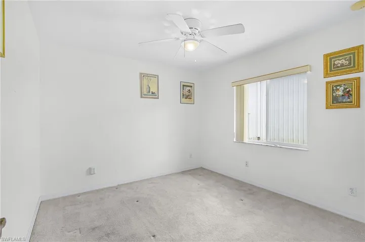 Carpeted empty room featuring a ceiling fan and baseboards