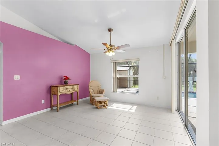 Living area featuring a ceiling fan, lofted ceiling, and light tile patterned floors