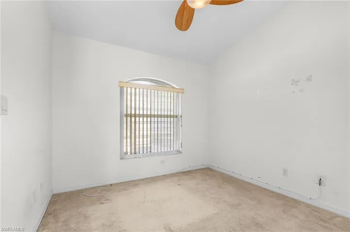 Empty room featuring a ceiling fan, carpet floors, and lofted ceiling