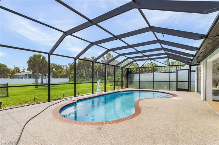 View of swimming pool featuring a lawn, a sunroom, glass enclosure, and a patio