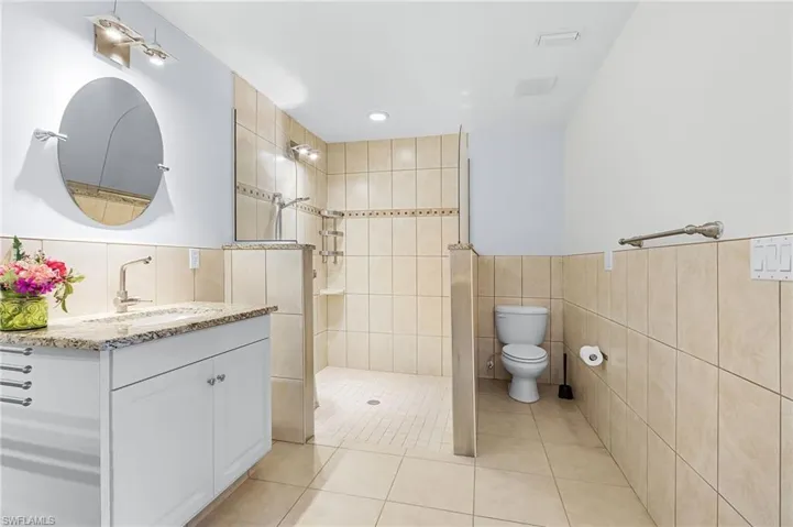 Bathroom with vanity, tile walls, walk in shower, light tile patterned floors, and recessed lighting