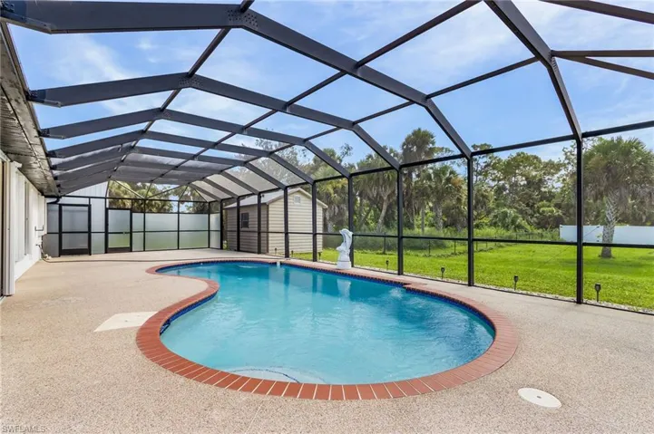 Outdoor pool featuring a sunroom, a shed, a lanai, a patio, and a lawn