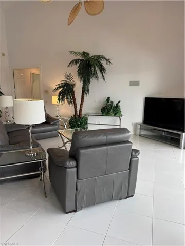 Tiled living room with visible vents, a towering ceiling, and a ceiling fan