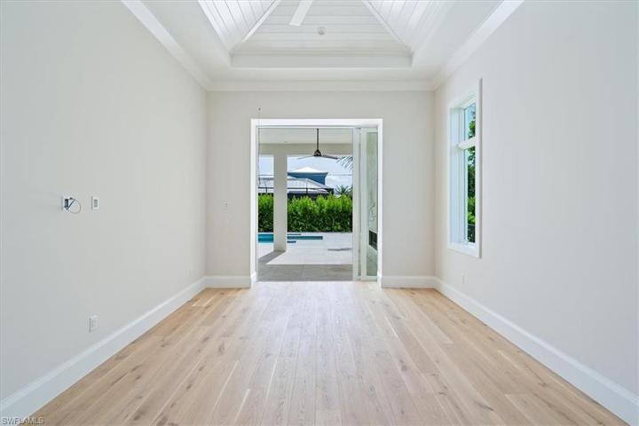 The primary bedroom features a vaulted ceiling with nickel gap treatment and ample natural light through the windows and sliding glass doors leading out the pool and spa.