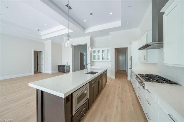 The kitchen features white & wood tone shaker cabinetry, Pompeii Misterio quartz countertops, and Thermador appliances with natural gas cooking. The walk-in pantry just around the corner offers ample storage.