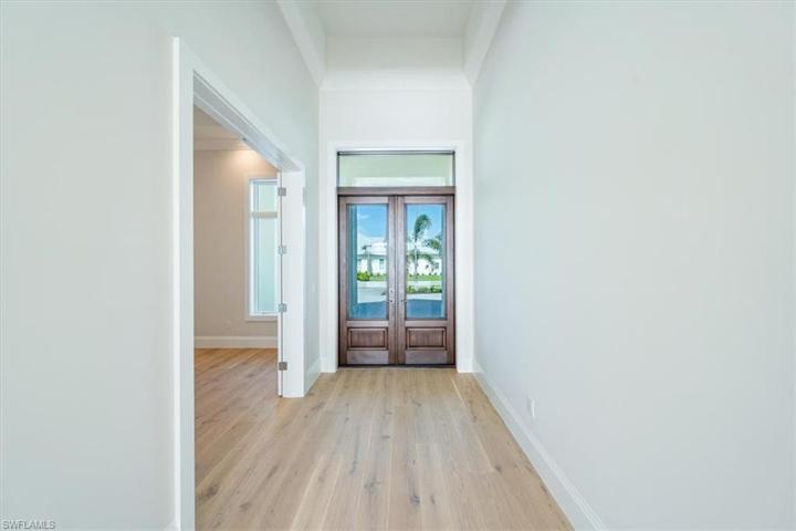The front door features impact glass and a deep walnut stain. Just inside, double doors lead to the office with large windows.