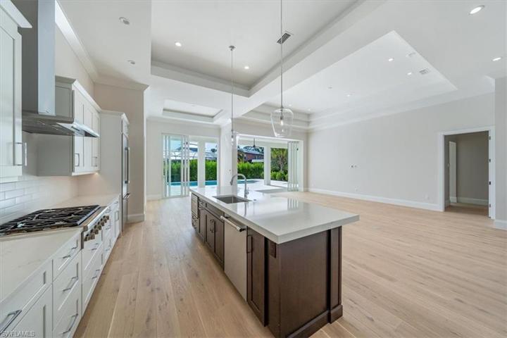 The kitchen overlooks the great room, open dining, and pocket sliders leading out to the pool deck with outdoor kitchen.