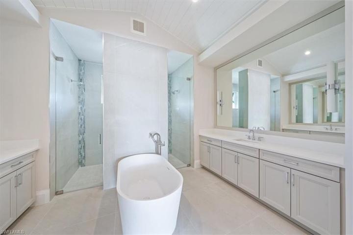 The spa-like primary bathroom features large scale tile, enormous shower with dual shower heads and hand shower, and dual vanities with storage.
