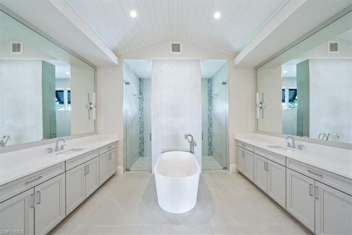 The spa-like primary bathroom features large scale tile, enormous shower with dual shower heads and hand shower, and dual vanities with storage.