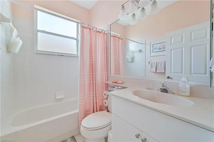 Full bathroom featuring toilet, vanity, and shower / bathtub combination with curtain