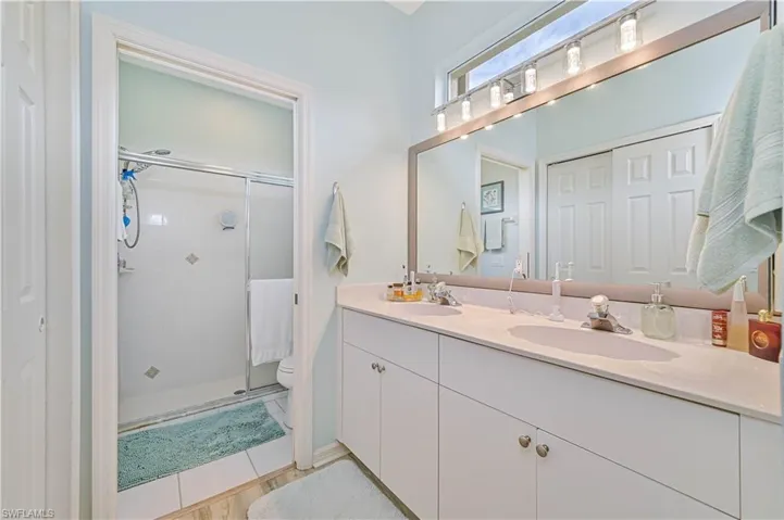 Bathroom featuring tile patterned flooring, toilet, a shower with door, and vanity