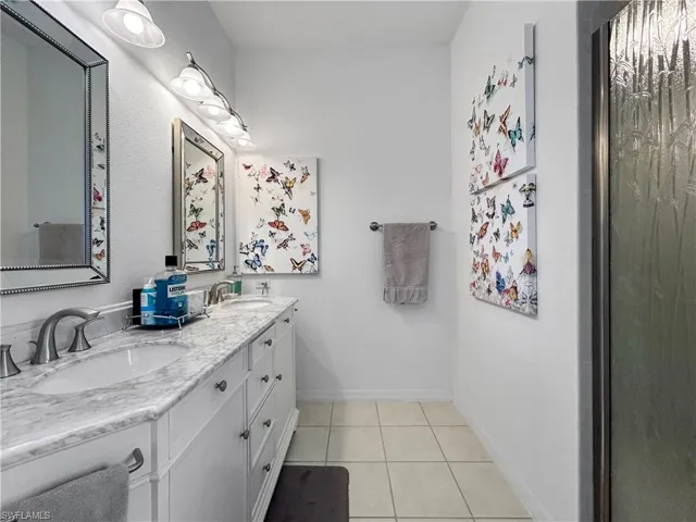 Bathroom with light tile patterned flooring and double vanity
